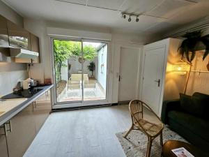 a kitchen and living room with a table and a chair at Havre de Paix - Les Sablon d'A Côté in Amiens