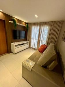 a living room with a couch and a flat screen tv at Apto Garcia 01 ao lado do Shopping Pantanal in Cuiabá