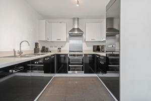 a kitchen with black and white cabinets and a sink at 3 Bed - Sleeps 7 - Hot-Tub - Free Parking in Hornchurch
