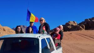a group of people standing on the roof of a truck in the desert at Traditions of Wadi Rum camp & jeep tour in Wadi Rum