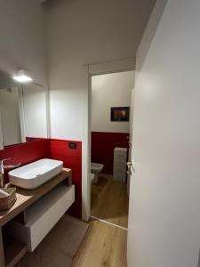 a bathroom with a white sink and a red wall at Margherita Home in Brescia