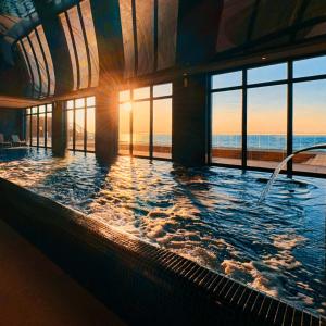 Una gran piscina con el sol brillando a través de las ventanas. en Sea View Smart & Garden VIP Apartment, en Międzyzdroje