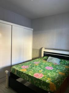 a bedroom with a bed with a green and pink blanket at Casa temporada in Rio das Ostras