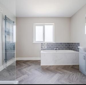 a white bathroom with a tub and a window at Fully refurbished house Belfast in Belfast +22 photos