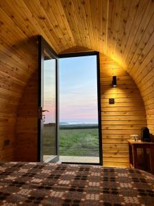 a bedroom with a large window in a wooden room at Cosy Cabin with sea view in Broad Haven