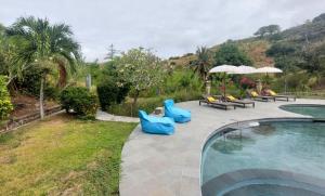 a swimming pool with people sitting in blue chairs next to a pool at Lombok Villas, Villa KuraKura in Labuhanpoh