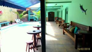 un patio con mesas y taburetes junto a una piscina en Suítes Casa Verde, en Arraial do Cabo