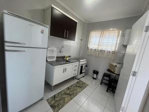 a kitchen with a white refrigerator and a sink at Casa 1 km da Praia Enseada com Garagem in Guarujá +5 photos