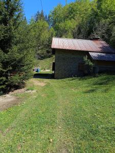a brick building with a tin roof in a yard at Bujtina Ora e Shales in Boge