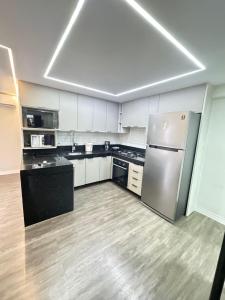 a large kitchen with a stainless steel refrigerator at Suites Premium 2 quartos in João Pessoa