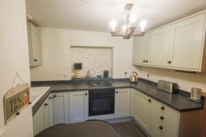 Una cocina con gabinetes blancos y una encimera negra. en The Oak House, en Glastonbury