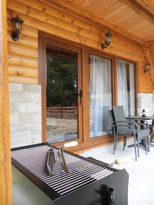 a grill on a patio with a table and chairs at Vikendica Monte Pino Romanija in Sokolac