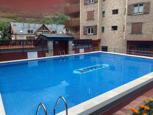 a large blue swimming pool next to some buildings at Estudio 2-4 personas en Vielha-Baqueira in Vielha