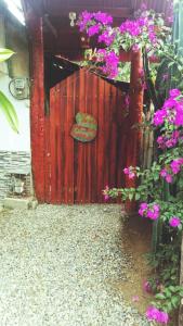 una recinzione rossa con fiori viola e un cartello sopra di Hostel Cattleya a Palomino