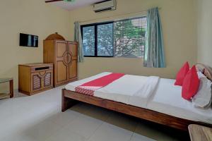a bedroom with a bed and a cabinet and a window at Hotel O Green Hills Resort in Sopāra