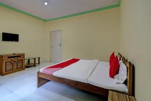 a bedroom with a bed and a dresser and a television at Hotel O Green Hills Resort in Sopāra +30 photos