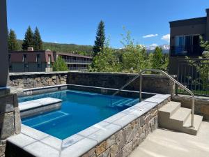 a swimming pool with a stone wall and stairs at Hideaway Station TS 23 - New in Downtown Winterpark in Winter Park
