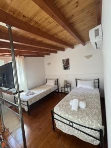 two beds in a room with wooden ceilings at Villa Mitsialis in Lákka