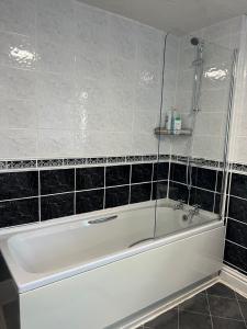 a white bath tub in a bathroom with black tiles at Stylish and Spacious two-bedroom Apartment in Blackpool +22 photos