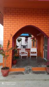 Un edificio de ladrillo naranja con mesas y sillas en un patio. en Gulariya Home Stay, en Bākhri Kharka