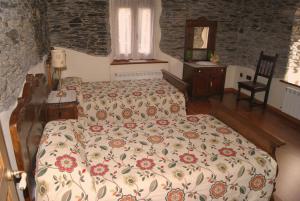 a bedroom with two beds and a stone wall at Apartamentos Rurales Los Galpones in Coaña