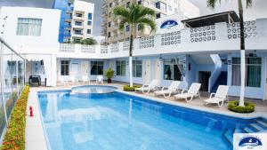 a swimming pool with chairs and a building at Grand Pacific Ocean in Tonsupa