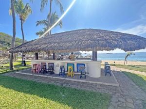 eine Strandbar mit Stühlen und Strohdach in der Unterkunft Beachfront unit with ocean view, pool, fiber optic in Bahías de Huatulco