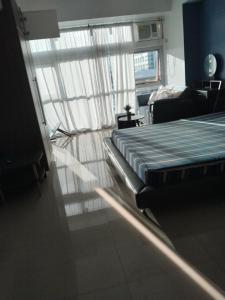 a bedroom with a bed and a couch and a window at Brees Place in Manila