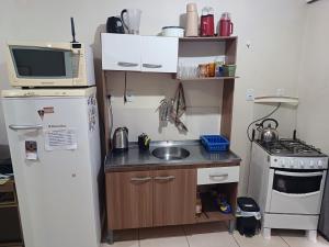 une petite cuisine avec un réfrigérateur et un micro-ondes dans l'établissement Apart próximo a Unimed, Catedral e HSA de 2 quartos com 2 Ar, mini-Academia e garagem no Centro-sul, à Santo Ângelo