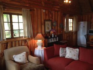 salon z czerwoną kanapą i 2 krzesłami w obiekcie Willowbrooke Cottage w mieście Himeville