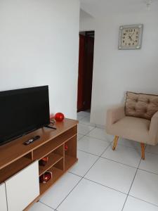 a living room with a television and a chair at Apartamento 2 quartos próximo ao Parque do Povo no centro de Campina Grande in Campina Grande