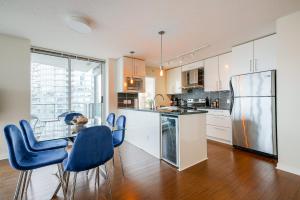 cocina con sillas azules, mesa y nevera en Gorgeous Unit with Beautiful City Views, en Vancouver