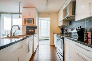 Una cocina con gabinetes blancos y encimeras negras. en Gorgeous Unit with Beautiful City Views, en Vancouver