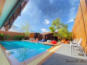 a swimming pool with chairs next to a house at Sand Dollar Boutique Hotel in Bang Sare