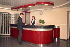 a man and a woman standing at a red counter at Gornyak Hotel in Shakhty