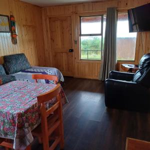 a room with a bed and a couch and a table at CABAÑAS MAR BRAVA in Ancud