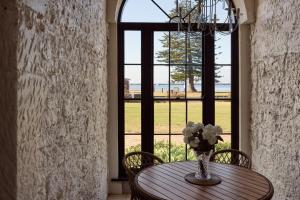 a vase of flowers on a table in front of a window at The Customs House Port MacDonnell in Port MacDonnell