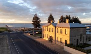 a building on the side of a road next to the water at The Customs House Port MacDonnell in Port MacDonnell