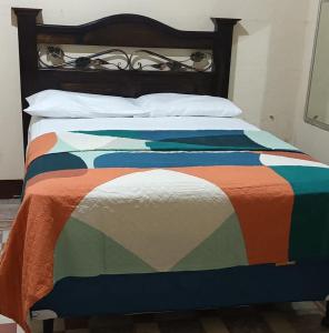 a bed with a colorful comforter and pillows at Hotel Casa don Angel in Las Victorias
