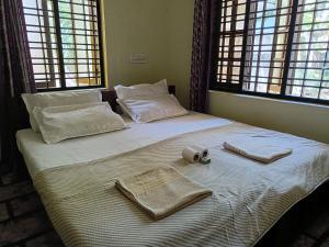 a large bed with two towels and two windows at Elara Beach Home Stay in Alleppey +43 photos
