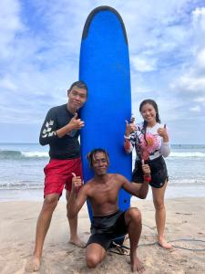 MantaakにあるBudalsurfingの三人のサーフボードを持って浜辺に立つ