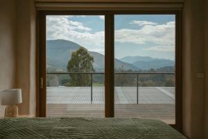 a bedroom with a large window with a view of a mountain at French Farmhouse in Wandiligong