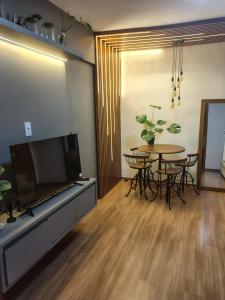a living room with a tv and a table with chairs at Quarto Privativo em Apto compartilhado in Uberaba