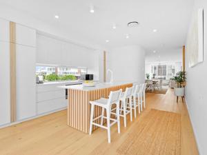 Baja on Cylinders - Beachfront Bliss في كينغسكليف: مطبخ بجدران بيضاء وكاونتر مع الكراسي البيضاء