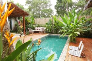 a swimming pool in a garden with chairs and a table at Casa Kasoy - Private pool villa in El Nido