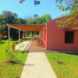 a red building with acovered walkway in a yard at Solar de Campo in Villa Elisa