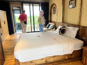 two people standing in a bedroom with a large bed at Duong Lam Eco Home in Sơn Tây
