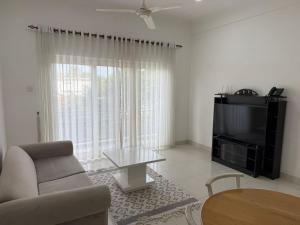 Una sala de estar con un sofá, un televisor y una mesa. en De Seram Loft Mount Lavinia #M, en Mount Lavinia