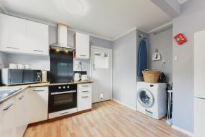 a kitchen with white cabinets and a washer and dryer at Picton Central - Picton Holiday Home in Picton