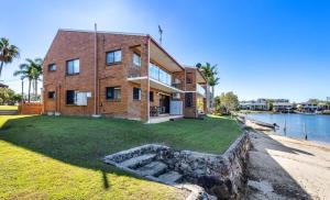 a brick house on the shore of a body of water at Barooga1- Mooloolaba Canal Front Apartment in Mooloolaba